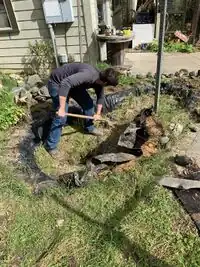 Image 1: Pond Deconstruction began with digging out the grass, clay, and rocks from the bottom of the pond.