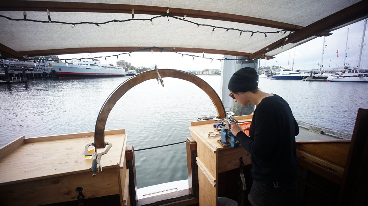 someone building a metal arch with a beautiful waterfront view ahead