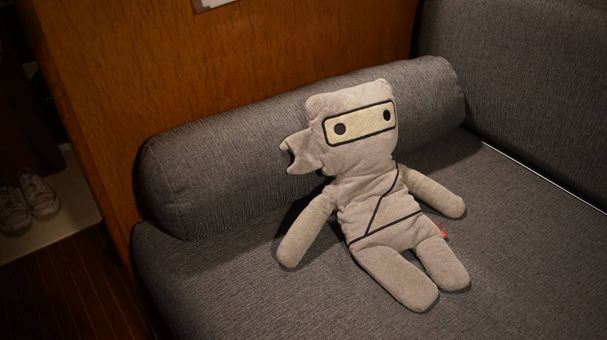 little ninj laying over a cylindrical cushion and looking very comfy