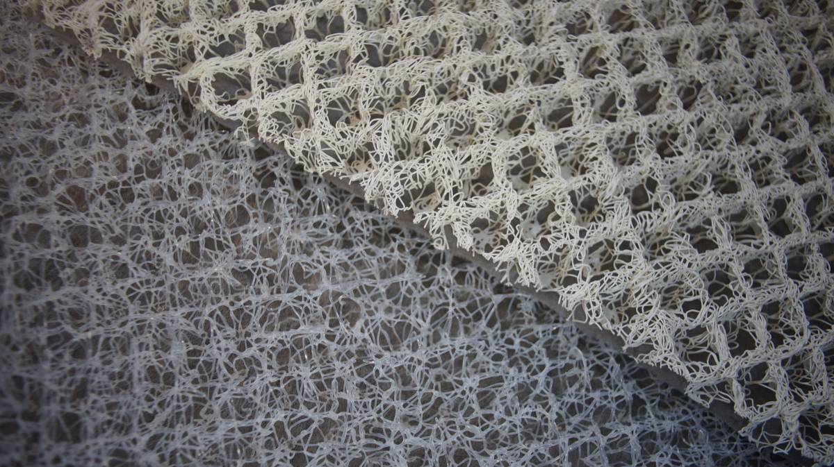a comparison of two different types of mesh underlining, one is white and more organized while the other is gray and more random