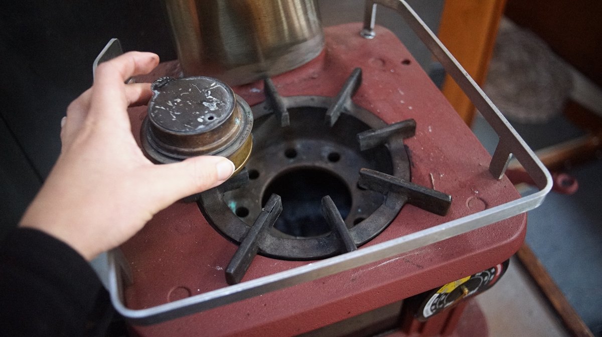 a hand holding a trangia burner