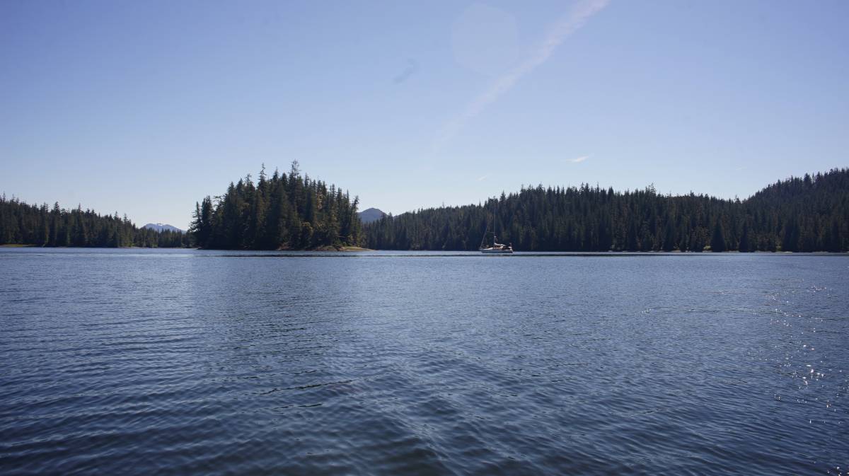 pino anchored alone in snug cove, anchored behind a small islet on a clear day