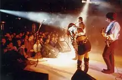 Three musicians on the stage above the audience.