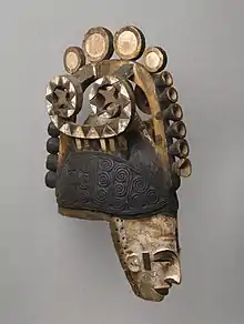 Igbo maiden spirit helmet mask (Agbogho Mmwo); early 20th century; 50.2 x 14.6 x 30.5 cm (193⁄4 x 53⁄4 x 12 in.); Brooklyn Museum. This helmet mask has long narrow face, painted white; narrow protruding sharp nose; slit eyes; open mouth showing teeth; small ears