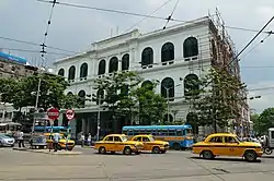 Three-story building, viewed from the street with trees in the foreground