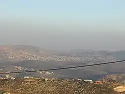 In the front, beneath the telephone cable, is mount 725, an illegal Israeli outpost of Yitzhar. Beneath it, crossed by the telephone cable, is Einabus. Covering most of the farther area is the municipality of Qabalan. Behind the right side of Qabalan is Talfit, and behind it is Qaryut. Behind the middle of Qabalan is Ahijah.