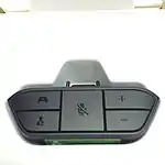 Xbox One Stereo Headset Adapter, a black plastic attachment that plugs into the bottom of the Xbox One Wireless Controller and provides a standard 3.5 mm stereo headset jack with microphone contact. The adapter itself is roughly trapezoidal and has five buttons on its face; two buttons on the left to balance audio output between in-game chat (bottom) and game (top); a large center button to mute the chat microphone; and two buttons on the right to increase (top) or decrease (bottom) overall volume.
