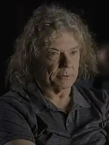close-up of Jerry Harrison wearing a dark sleeveless top, looking left of camera with a set facial expression