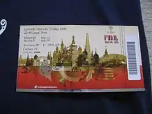 A ticket with a barcode strip on the right. The ticket is white on top half and red on the bottom, separated by images of the Moscow skyline in gold. In the top left corner is the seat information and the top right has the UEFA Champions League logo and the words "Final Moscow 2008".