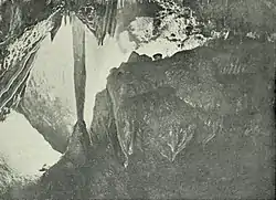 Calcite column and flowstone formations in a grainy black-and-white photo