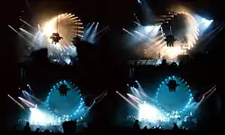 Four images, arranged to form a rectangle, of a darkened concert venue. The stage is dominated by a circular pattern of lights which surround a projection screen. Members of the audience are silhouetted in the foreground.