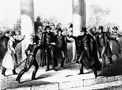 Several people in a crowd, man aims a gun at Jackson