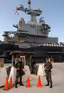 The Naval Support Activity Souda Bay's Security Department soldiers stand a security watch in front of the French aircraft carrier FS Charles DeGaulle (R 91) as it docks at the Marathi NATO pier facility in Souda Bay.
