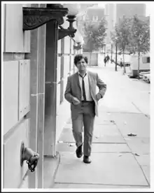 Walter Lively, wearing a suit and tie, walks down an empty city street in 1968.