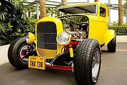 Front view of a vintage yellow car with a THX 138 plaque.