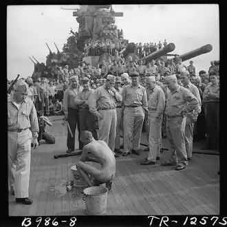 The crewmen of the battleship USS New Jersey watch a Japanese prisoner of war bathe himself before he is issued GI clothing. [Nov 1944]